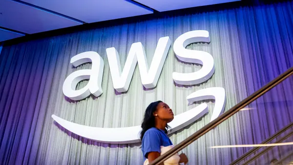 An woman passes an AWS logo on an escalator at the AWS re:Invent conference on Dec. 3, 2024 in Las Vegas.