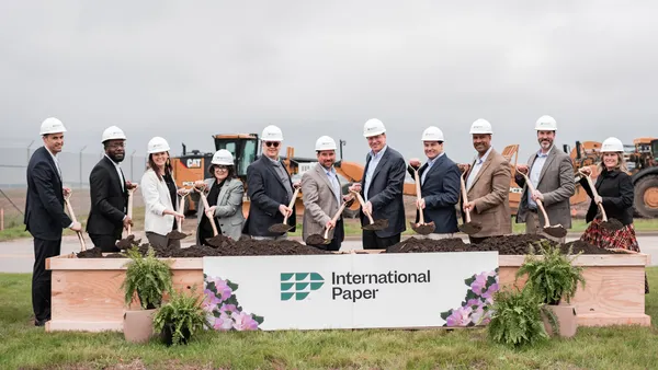 Line of people with shovels and hard hats and an International Paper sign