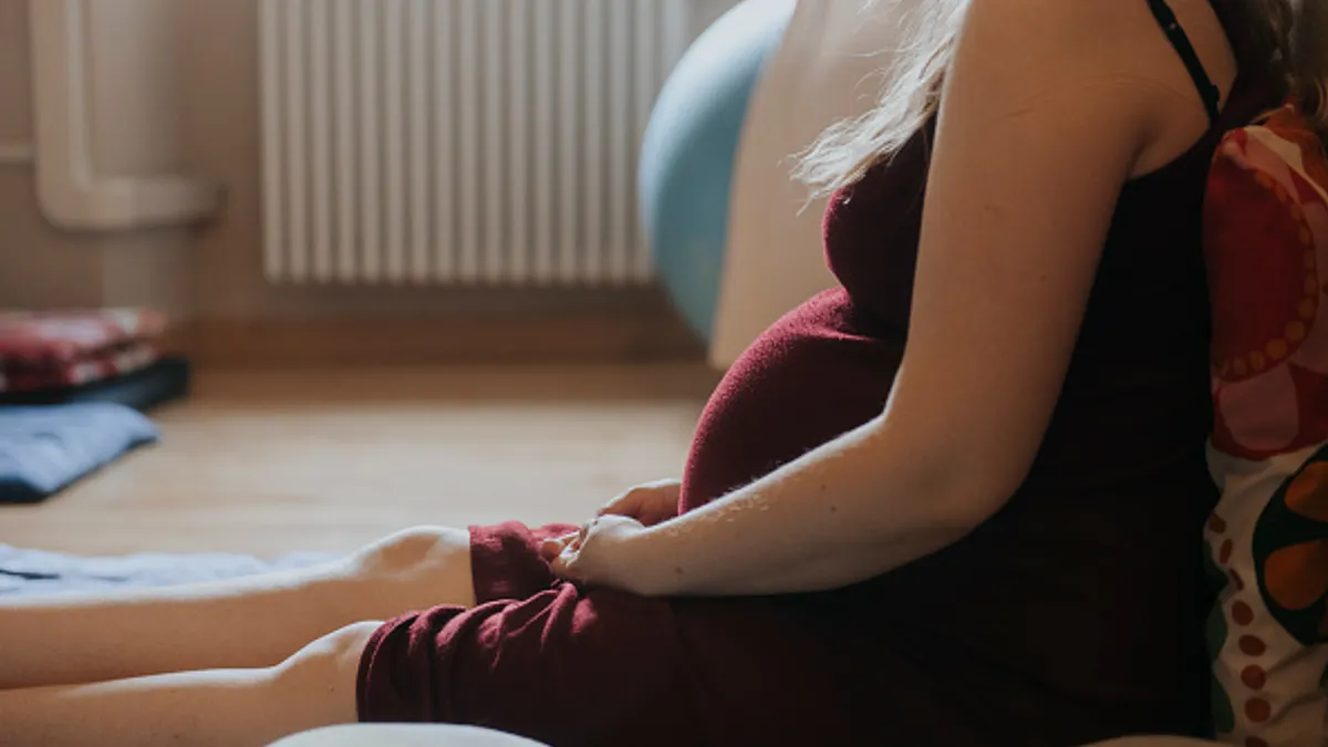 A pregnant woman sits on the floor