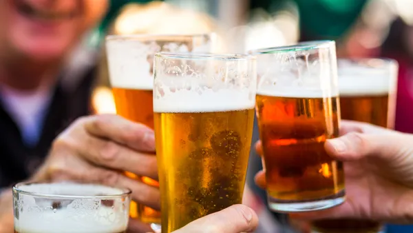 A close up shot of glasses filled with liquid held close together for a toast.