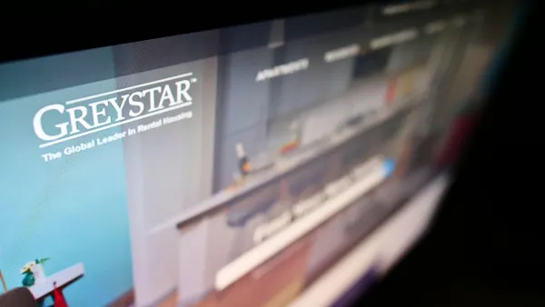 A high-angle view of the business website with the logo of the US apartment company Greystar Real Estate Partners LLC on the monitor.