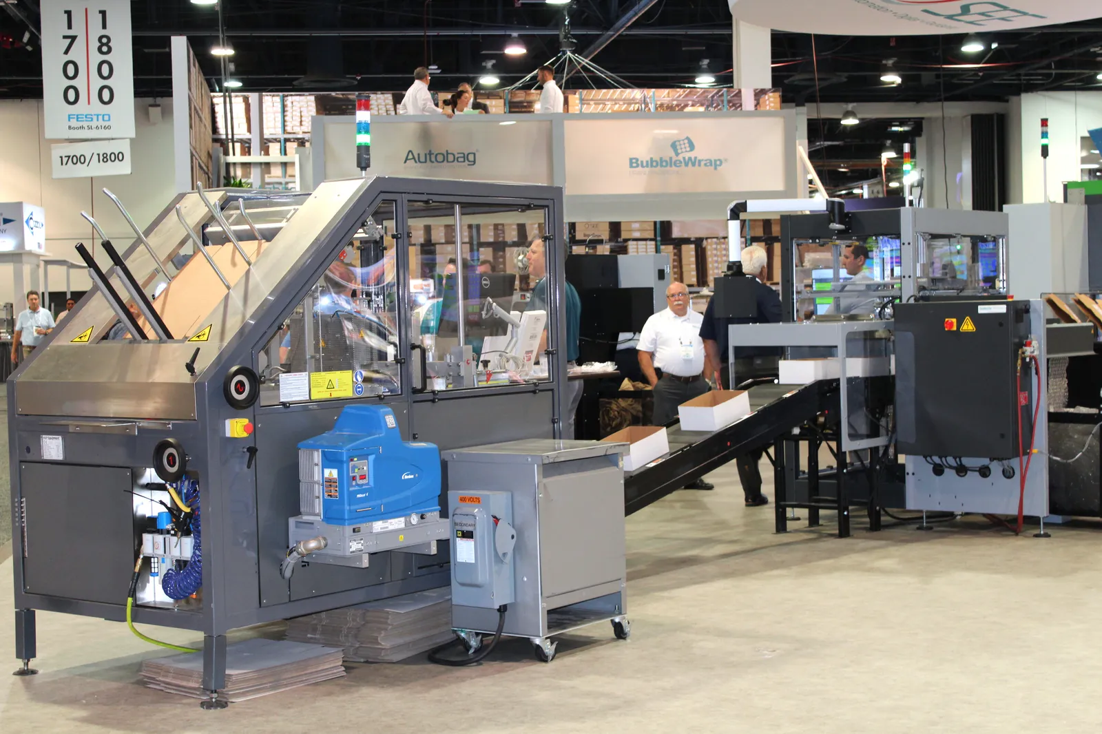 An industrial scale machine for manufacturing packaging is displayed at the Pack Expo trade show.