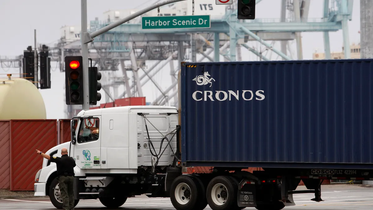 A harbor police officer redirects shipping container trucks an ocean port.