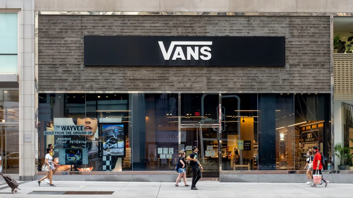 People walk in front of a Vans storefront.