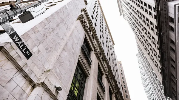 Looking up at tall buildings on Wall Street.