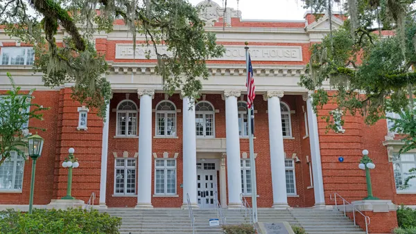 The front of a large brick courthouse building in the Beaux-Arts architectural style