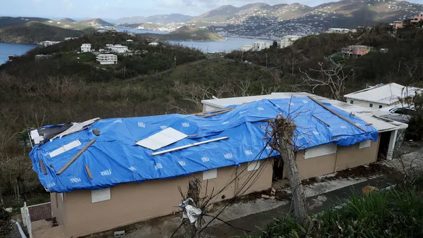 A blue tarp stamped with the FEMA logo covers the roof of a home damaged by Hurricane Irma.