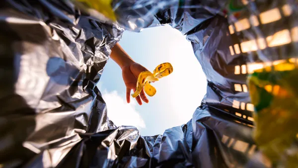 View of a person dropping a banana peel in a garbage can