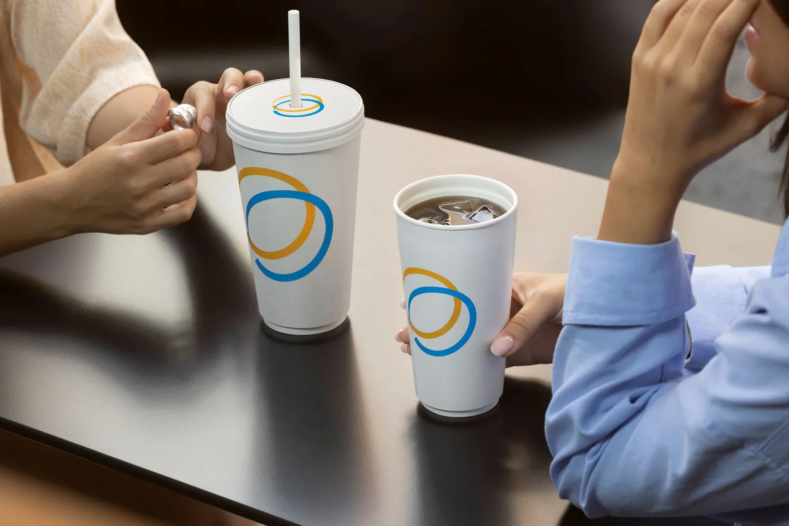 Two faceless people at a table with two beverages in Seda double-walled compostable cold cups