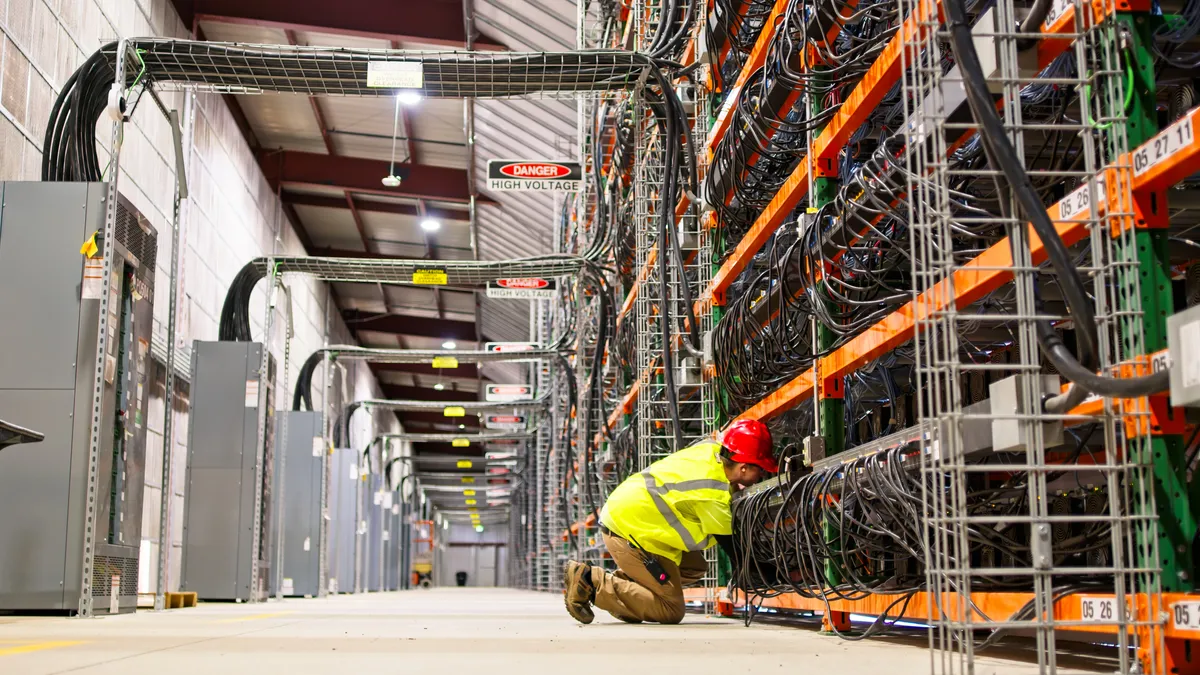 A man looks at data center wiring in a large warehouse.