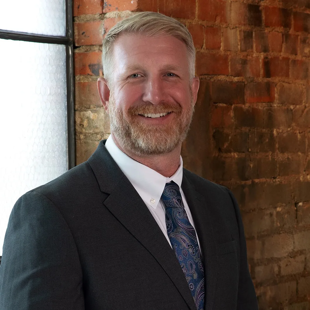 A man blond hair and a beard in a dark grey suit