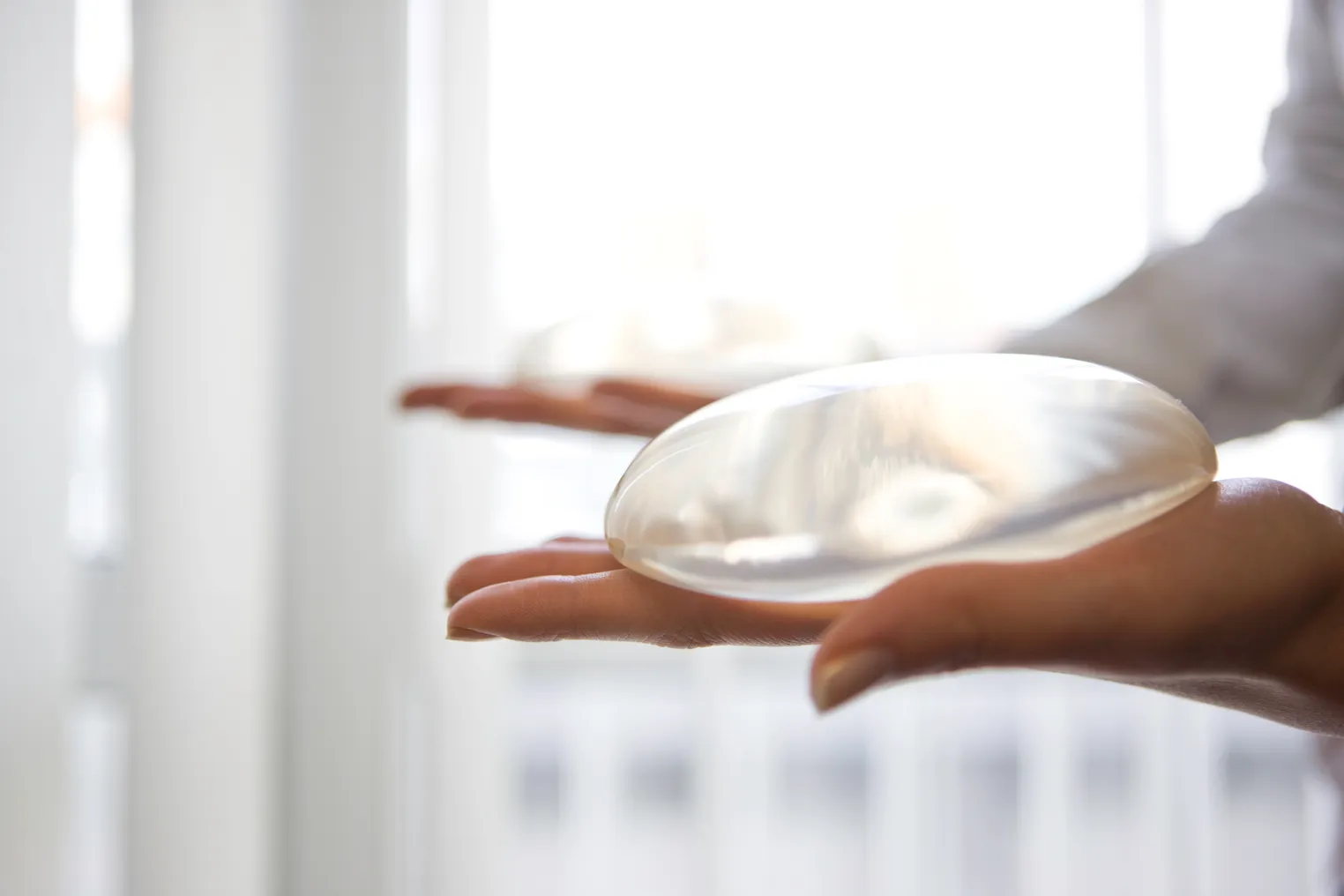 A person holds a transparent, oval shaped device