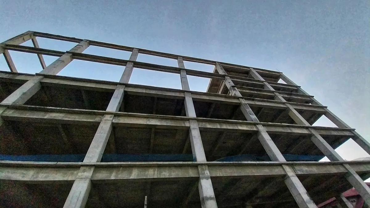 An abandoned apartment construction project, a massive building that remains incomplete and only displays empty box-shaped frames on each floor.