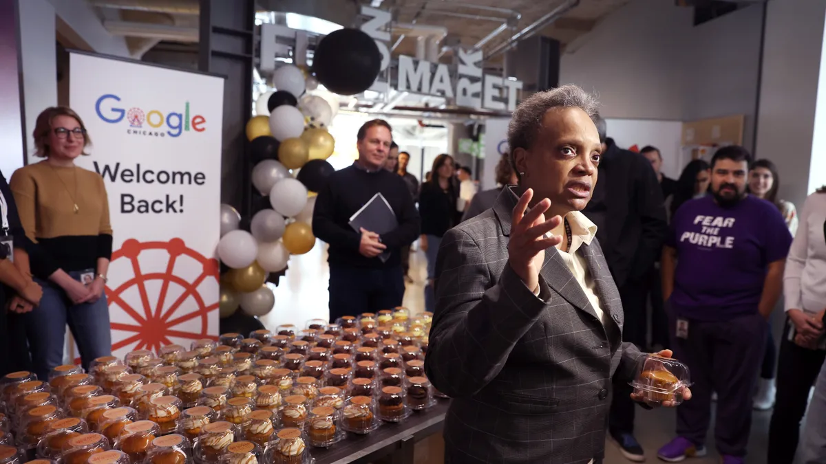 Former Chicago Mayor stands in front of a table welcoming Google employees back to the office.