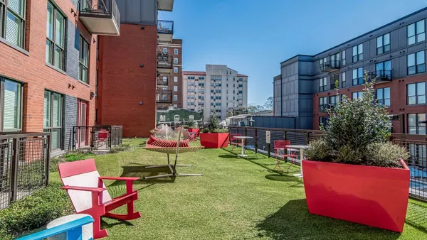 Tables and chairs on grass between two apartment buildings