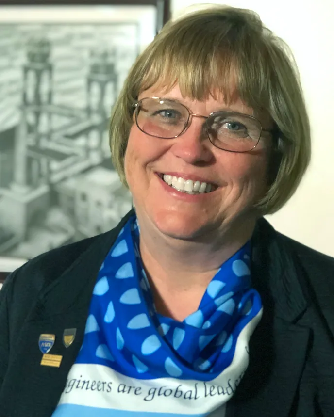 A smiling woman with a short blond bob haircut and glasses.