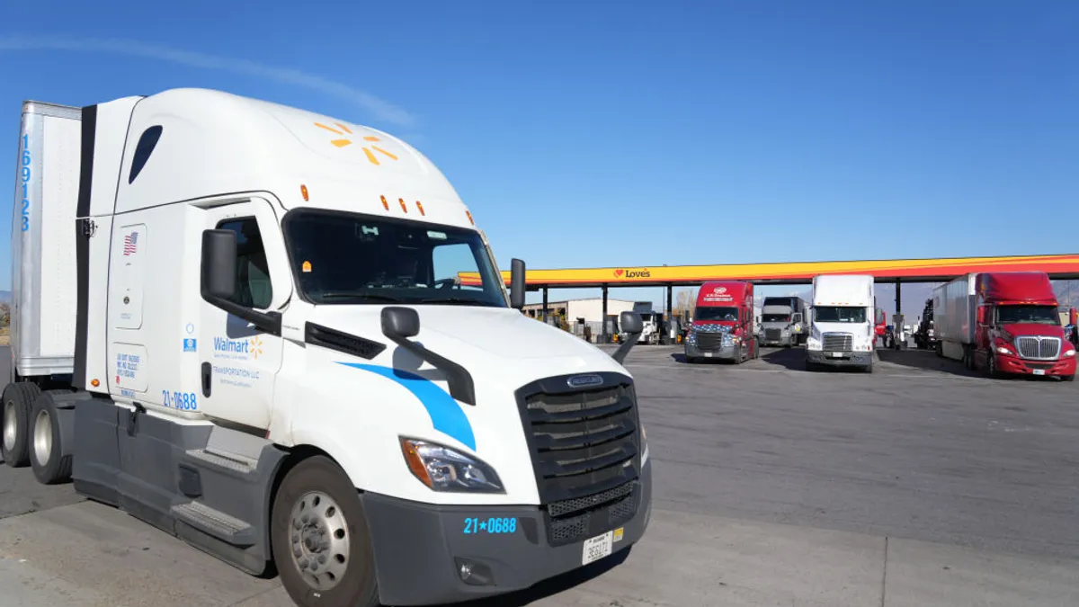 A Walmart truck in front of other trucks at a truckstop.