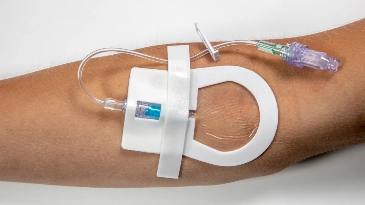 close up of an arm with a catheter, secured using a white foam sticker