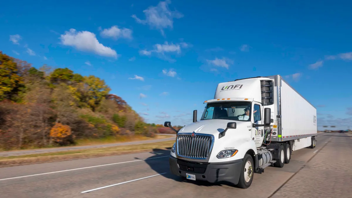 A UNFI truck drives down a highway in fall