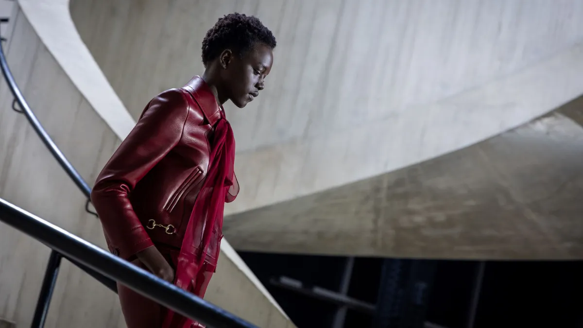 A model in a dark red top walks down stairs.