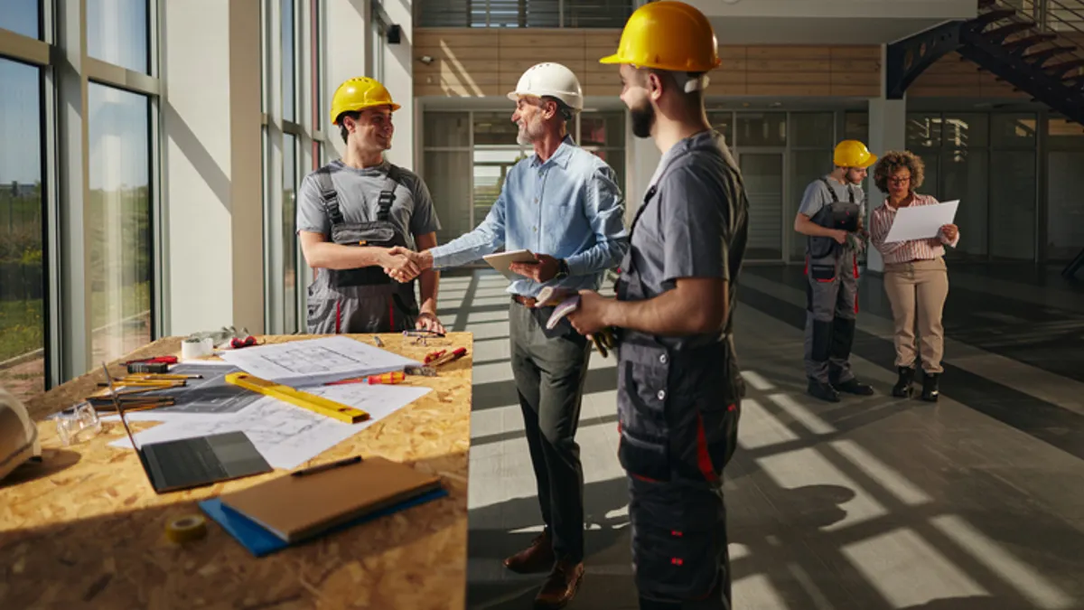 A group of people in construction safety gear shake hands on a jobsite.