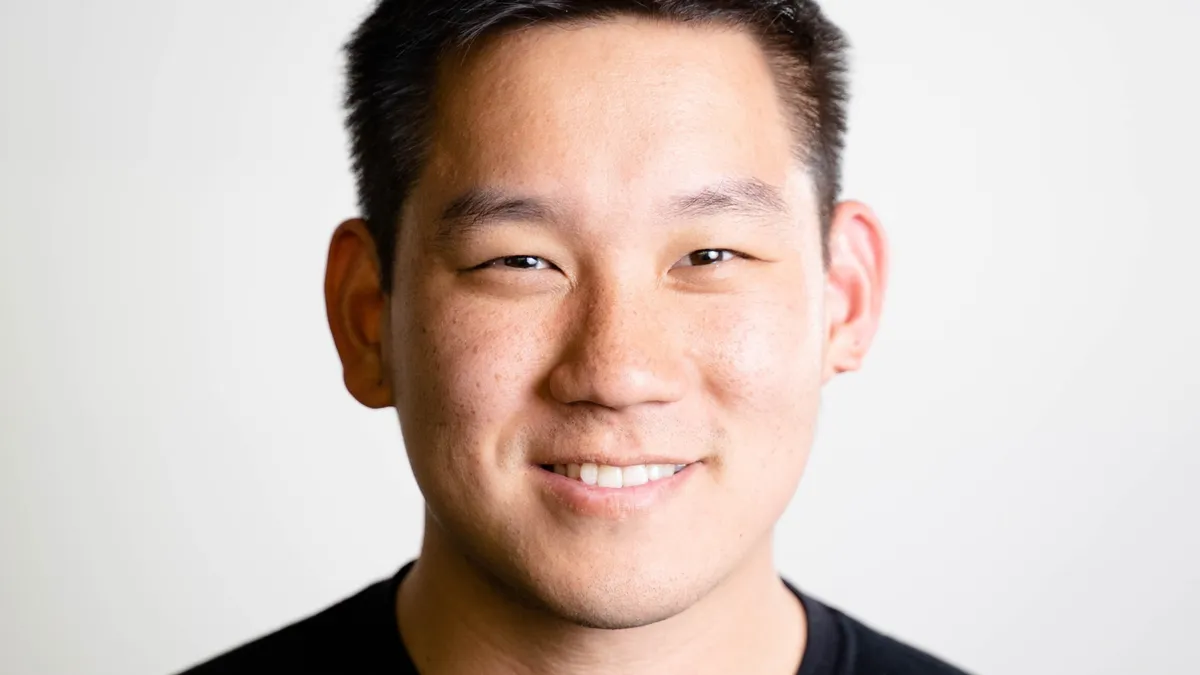 A headshot of a person smiling and wearing a black shirt.