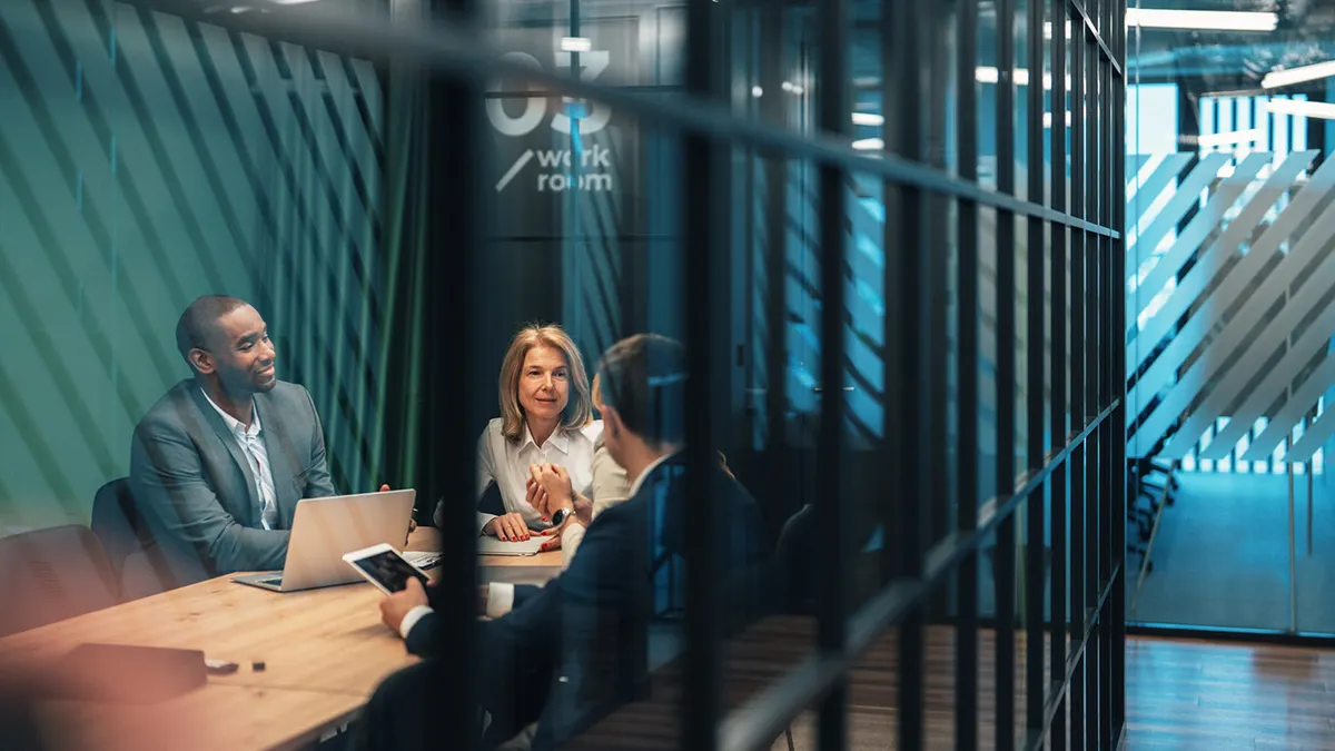 Business professionals sit together in a contemporary glass-walled office
