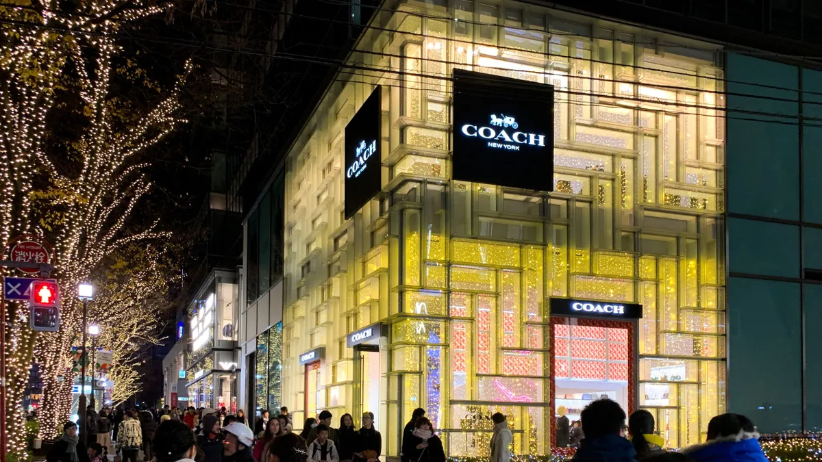 A Coach store in the evening, with people walking past.