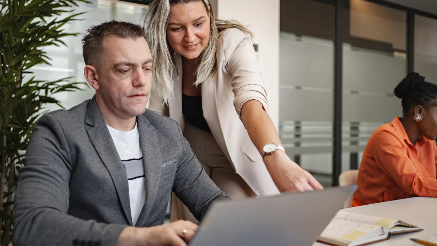 A businesswoman helps her colleague at the office.