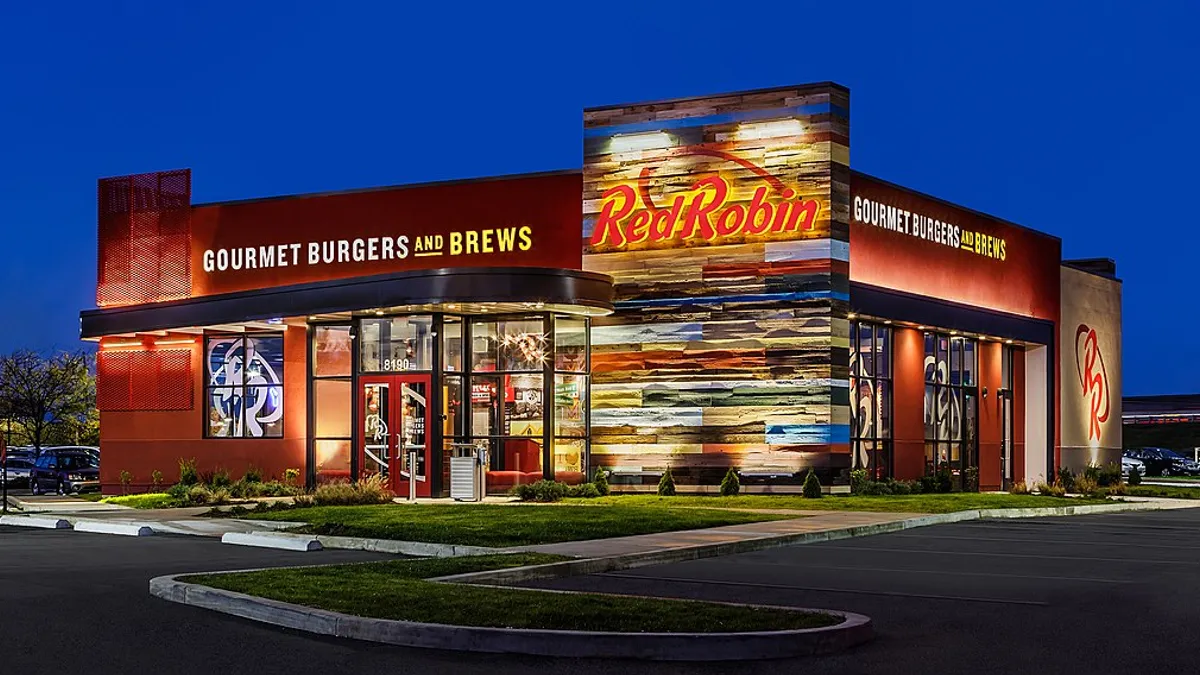 An exterior shot of a Red Robin restaurant, which is lit from inside, at night