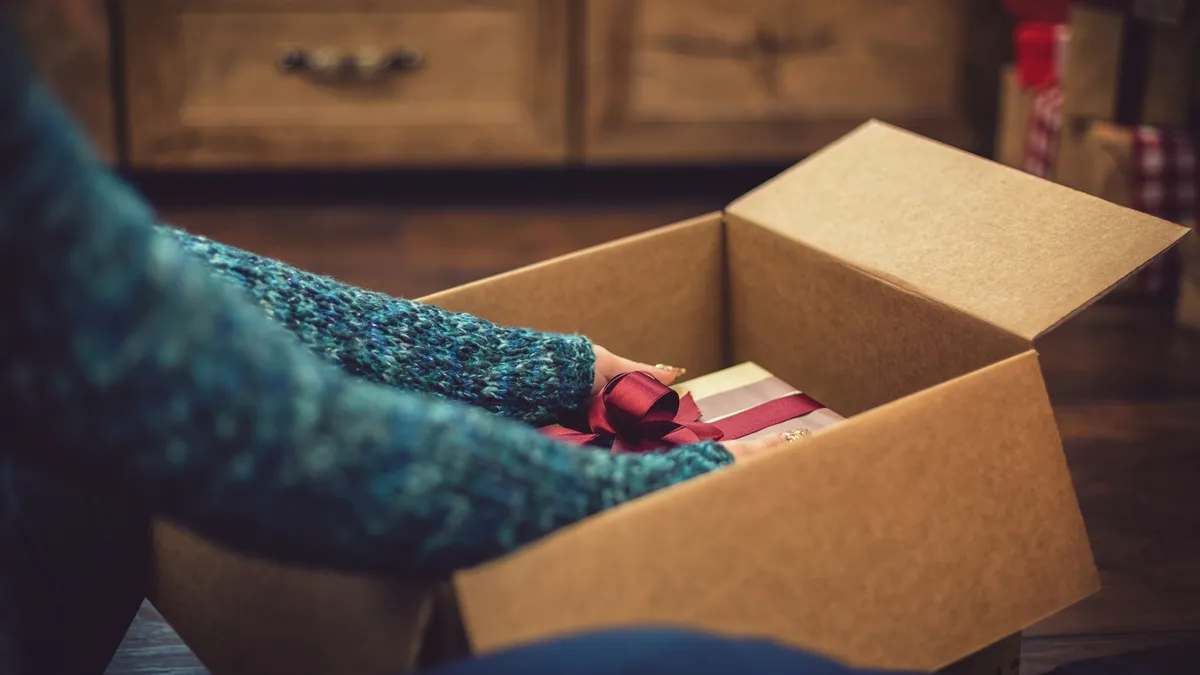 Person pulling a holiday gift out of a box.