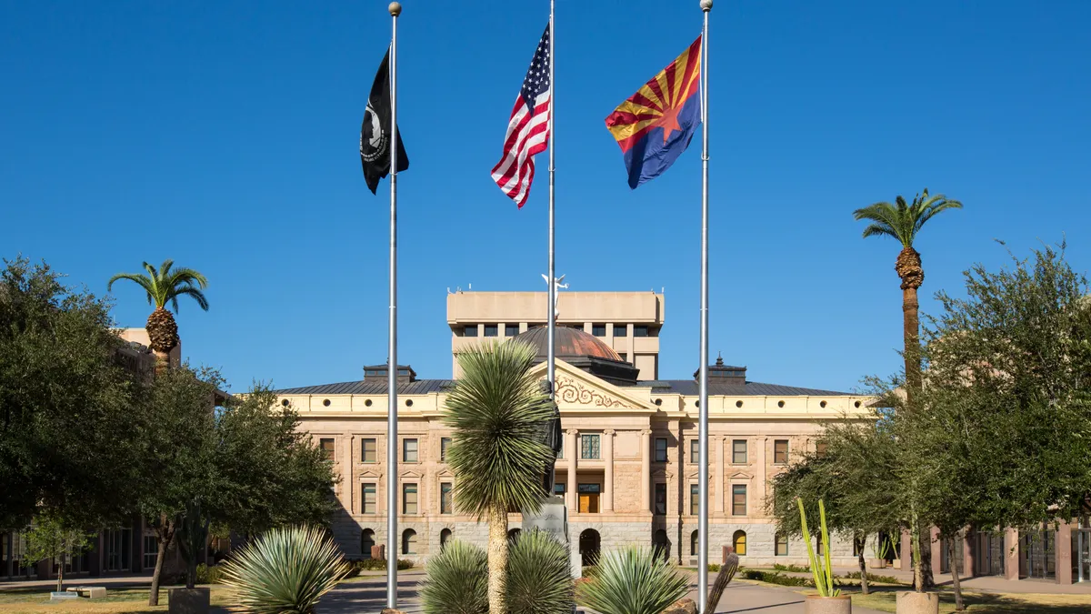 The outside of a building is seen and there are flags on poles in front of the building.