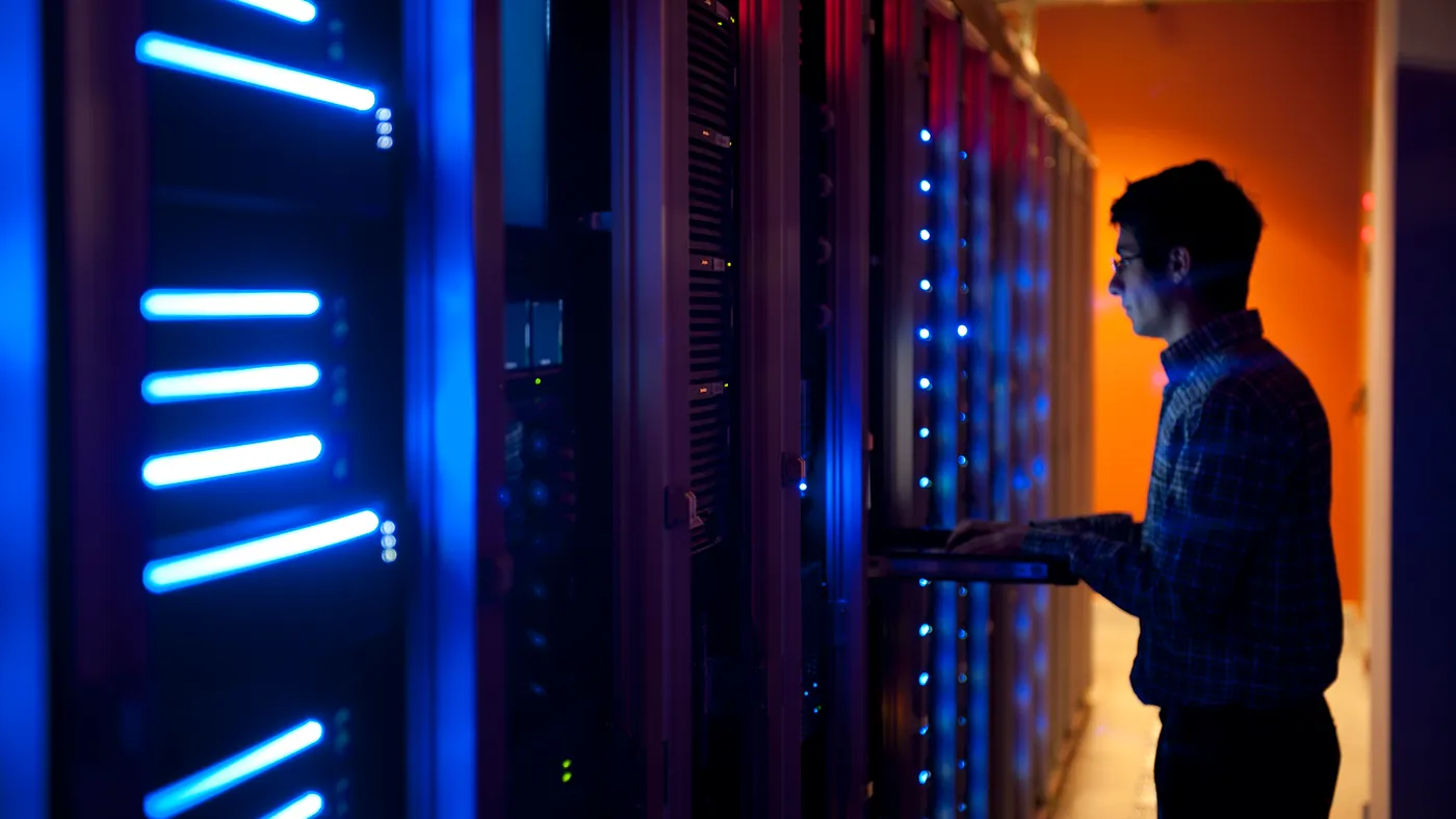 a technician reviews IT equipment in a server room