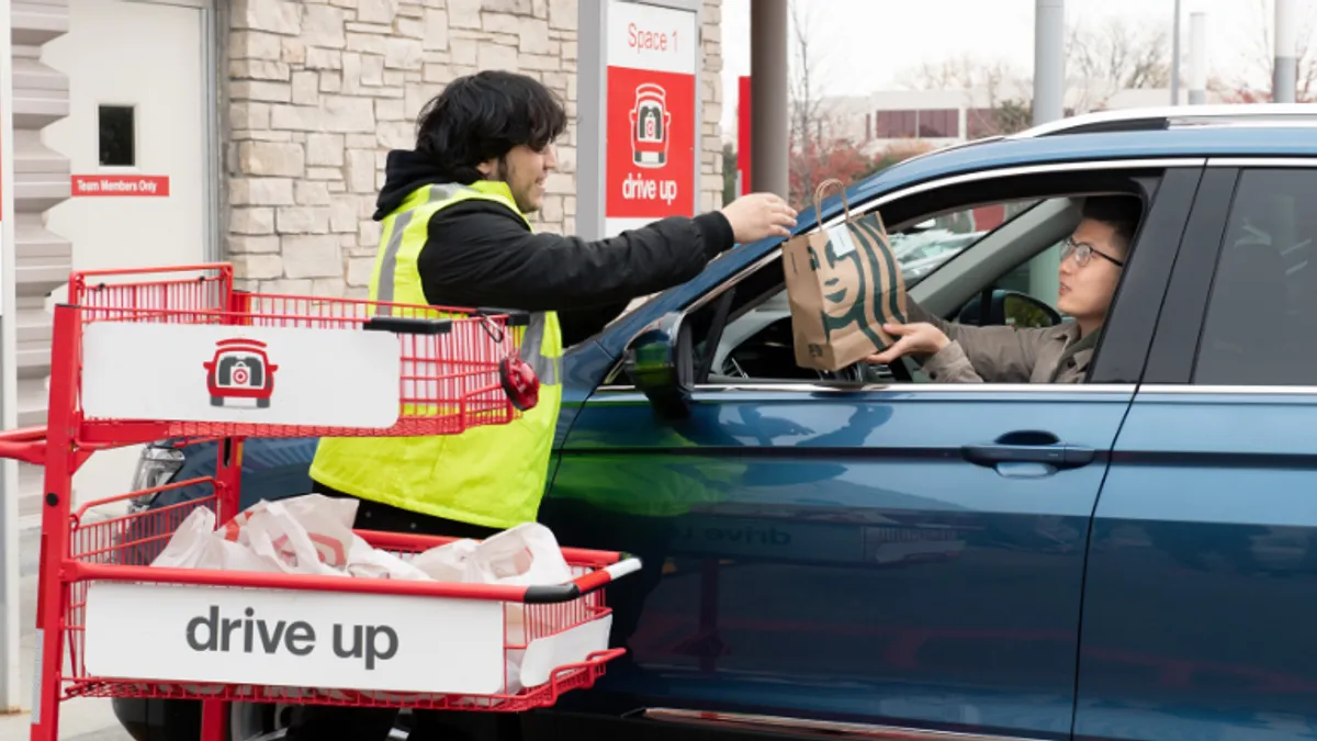 A Target worker hands a person in a car a Starbucks bag.