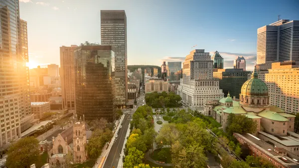 A shot of a city during the day with some foliage in the foreground.