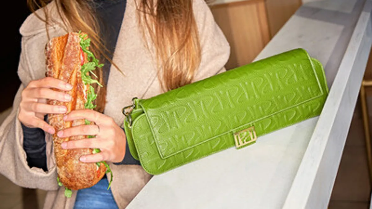 Person holding Panera Bread sandwhich and purse