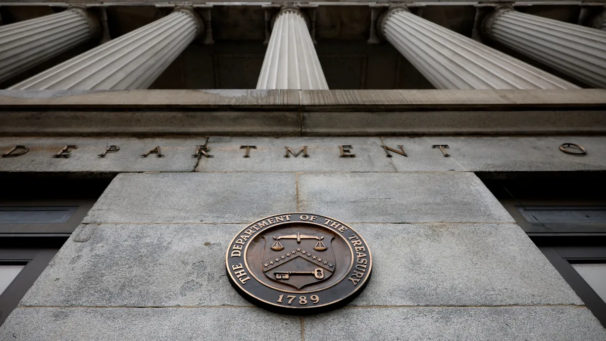 A close up of the Department of Treasury seal on the front of the headquarters with "the Department of Treasury" and "1789" on an outer circle and a shield with the scales of justice up top and a key.