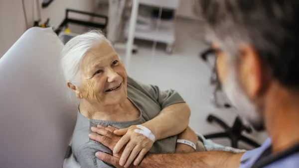 Friendly relationship between caregiver and happy eldery person during nursing at home.