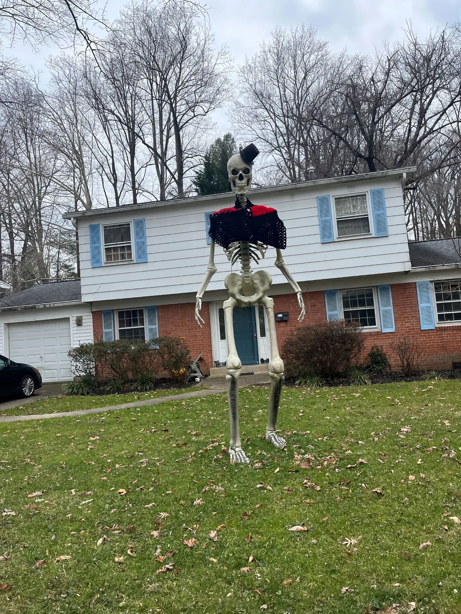 A skeleton dressed for winter in a yard.