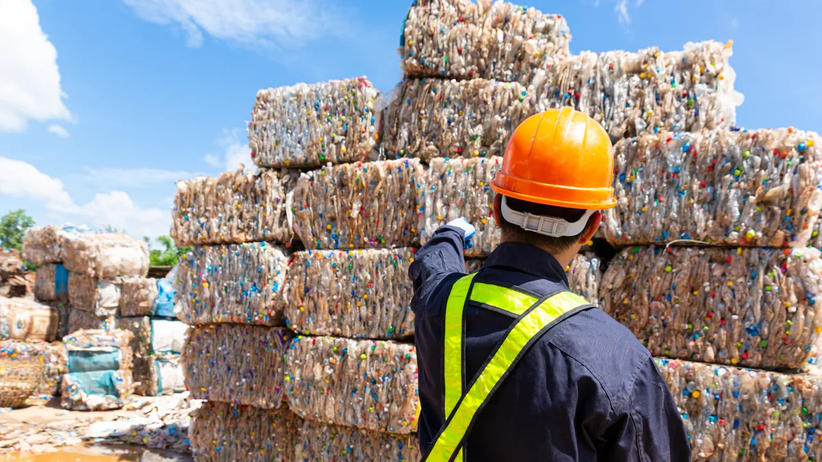 Person in hard hat standing in front of bales of plastic