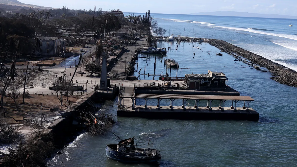 A aerial view shows a boat and pier damaged by fire.