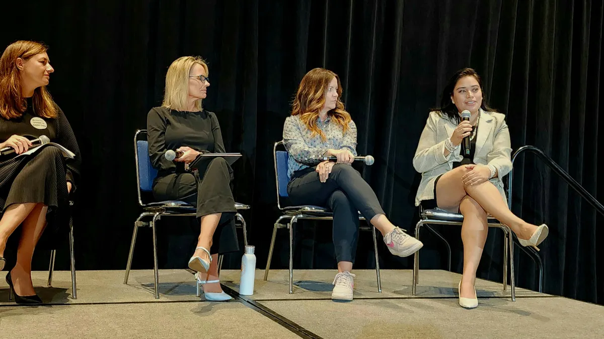 Four women sitting in chairs next to each other, and each holding their own microphone.