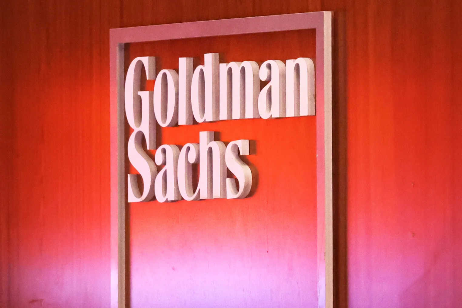 image of Goldman Sachs logo on wall with red background.