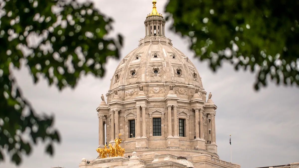 Dome of capitol building, with gold decorations, seen through tree branches