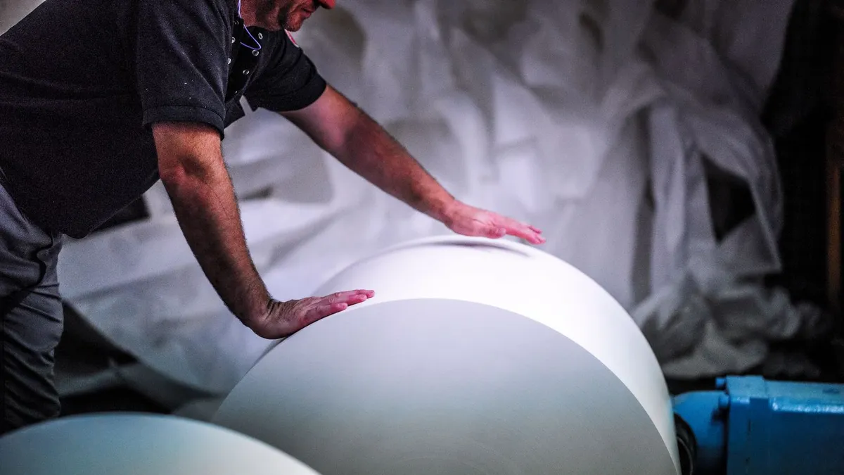 Person handling a roll of paper at an Ahlstrom manufacturing facility