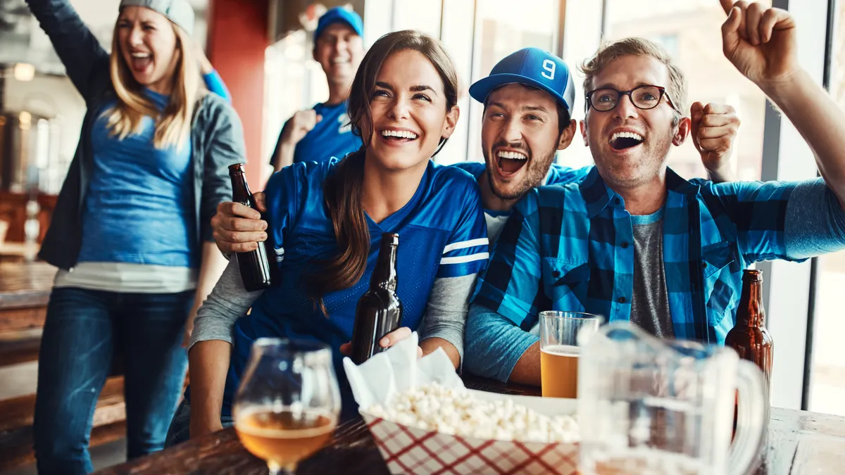 Group of friends cheering while watching a football game.