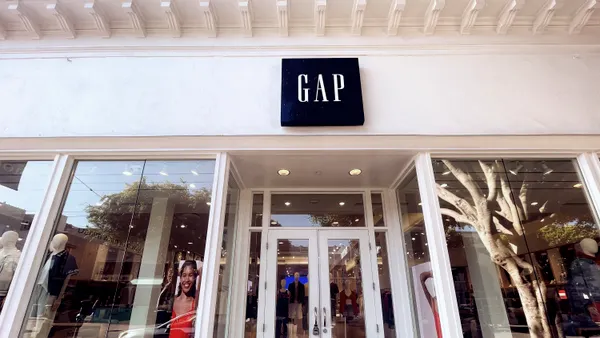 The outside of a Gap store, with a tree visible inside the window on the right side.