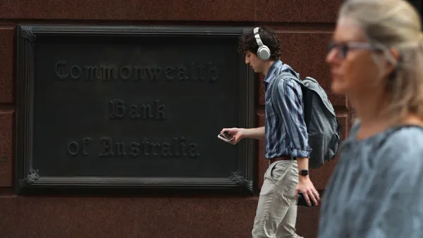 passersby on a streetscape with Commonwealth Bank of Australia signage in black