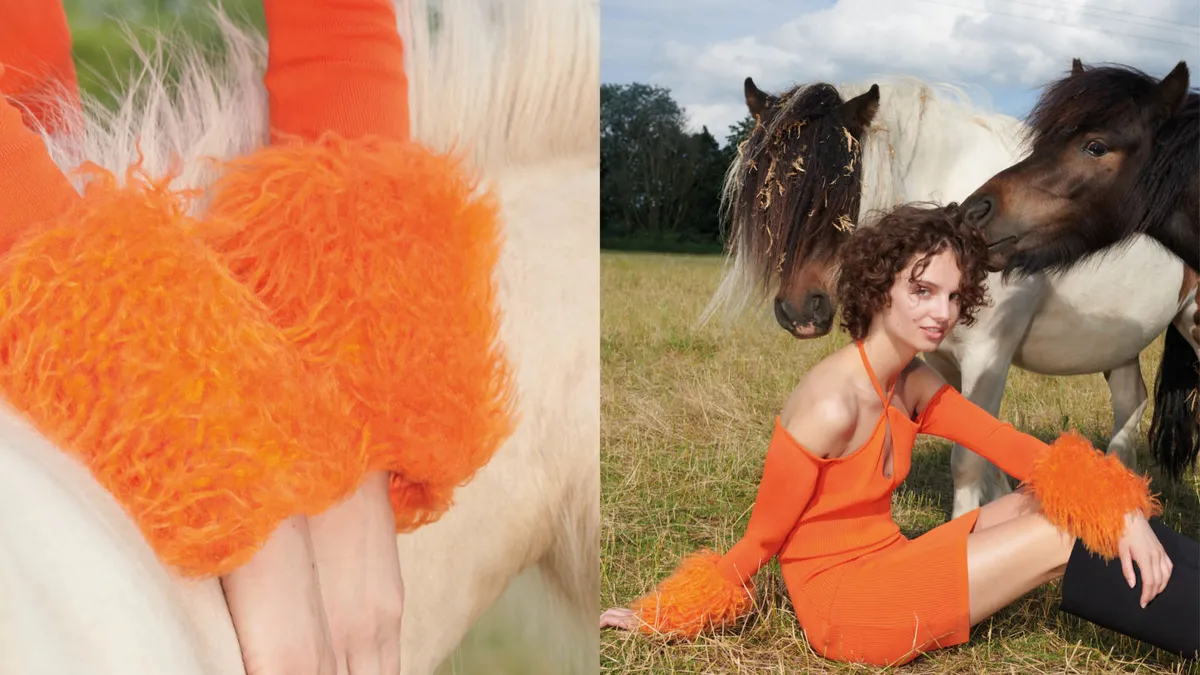 Close up of a model wearing an orange dress with feathered sleeves.