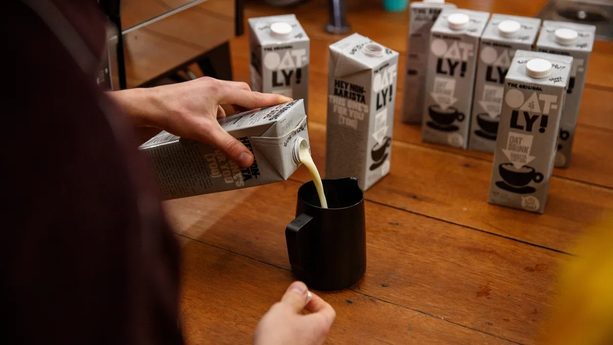 Person pouring oat milk into cup